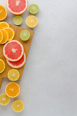 Colorful juicy summer oranges, grapefruits, limes, lemons on wooden board. Vertical, copy space