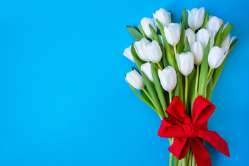 White tulips on blue background with a red bow