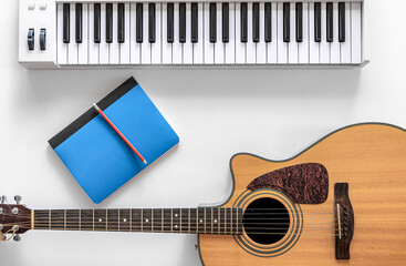 Acoustic guitar and musical keys on a white background, flat lay.