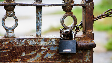 Rusty old padlock on metal gate closeup. Dirty lock on closed. lock on chains. Protection, security and safety concept. Private property entrance. old rusty iron texture.