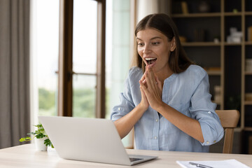 Happy surprised young businesswoman looking at computer screen, feeling excited celebrating...