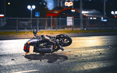 Motorcycle lying on asphalt after an road accident. Moto bike collision at night. Damaged...