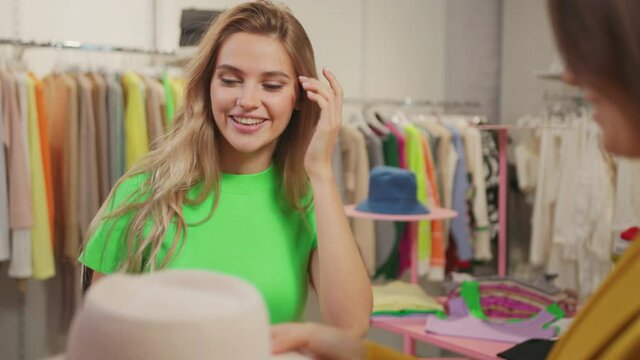 Happy couple of young female friends meeting in clothes store. Two attractive women choosing luxury fashion clothing items trying ln together.