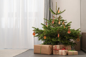 Fototapeta na wymiar Small christmas tree with natural decorations and gift boxes