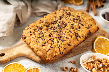 Homemade pumpkin pie with walnuts and chocolate on a wooden serving board closeup. Autumn traditional sweet pastries	