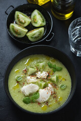 Black bowl with gazpacho soup made of green tomatoes and served with mozzarella, vertical shot, high angle view