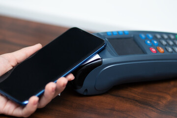 pos terminal,digital payment,hand with phone pays a bill at a restaurant or store