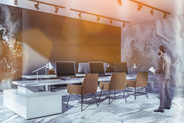 Businessman in office room interior with armchairs and computers