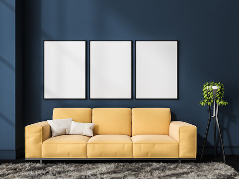 Three canvases on blue wall and yellow coach in living room
