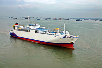 Naklejka premium Vessels, passenger ships and tugboats in port under cargo operations and underway. Port of Surabaya, Indonesia, January,2021