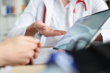 A woman doctor shows a tablet to a patient, close-up