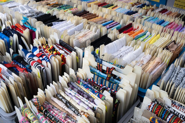 Fabric trims, waistbands and other haberdashery in various colors and sizes displayed in plastic crates in a market stall