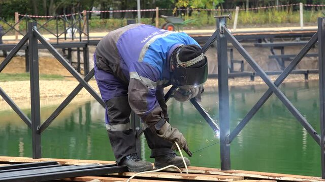 Manual Metal Arc Welding of the pond fencing in a park.
