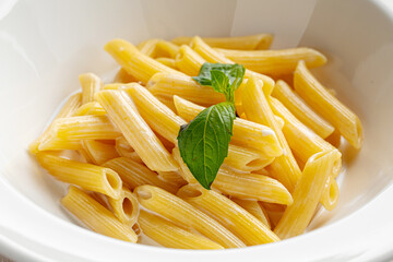 Cooked italian penne pasta macaroni garnish with basil