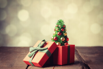 Christmas tree and red gift box on wooden table with bokeh