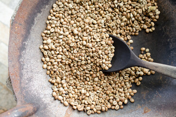 Obraz premium Traditional style roasted coffee bean in pan and wooden spoon in soft brown tone