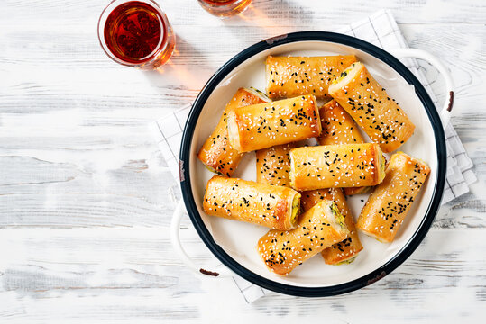 Turkish borek rolls with spinach and cheese. A traditional Turkish pastry rulo borek with black and white sesame seeds. White  wooden background. top view