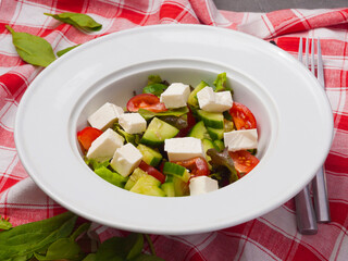 greek salad in a white plate on a red and white tablecloth
