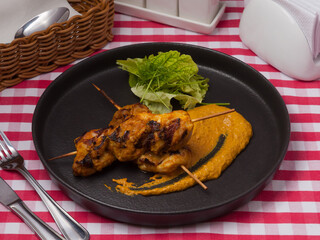 chicken skewers with curry on a black plate