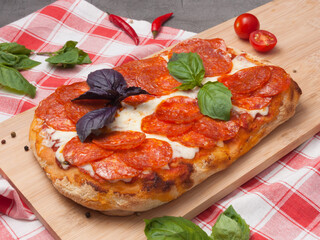 pepperoni pizza on Roman dough on a wooden board