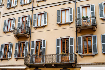 Fototapeta na wymiar Facade of the building with shutters and wrought-iron balconies. Milan, Italy