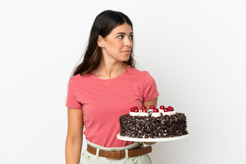 Young caucasian woman holding birthday cake isolated on white background looking to the side