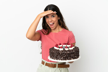 Young caucasian woman holding birthday cake isolated on white background doing surprise gesture while looking to the side