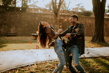 Young couple having fun with autumn leaves in the park