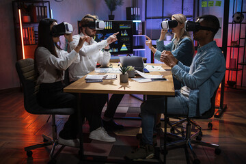 Group of four multiracial colleagues wearing VR headset during working meeting at office. Business...