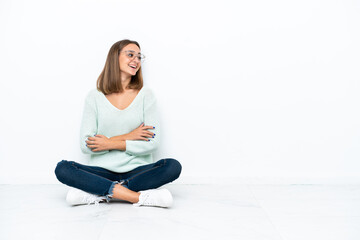 Young caucasian woman sitting on the floor isolated on white background happy and smiling