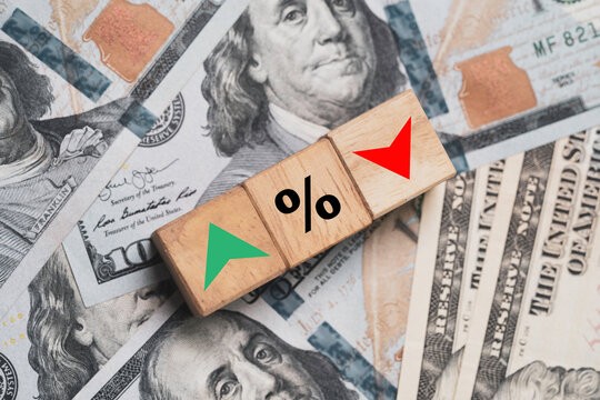 Increasing and decreasing sign with percentage on wooden cube block and dollar banknotes for forex currency exchange money transfer rate concept.