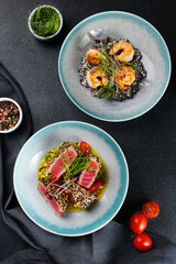 Japanese traditional salad with pieces of medium-rare grilled tuna and black risotto with shrimp and microgreen