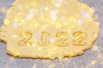 New Year 2022 Bakery concept. Cooking gingerbread cookies from raw dough with year 2022 numbers for new year and christmas cookies with beautiful bokeh, top view, flat lay. Happy new year 2022 concept