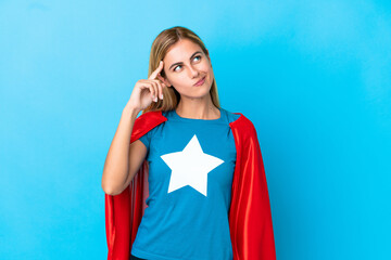 Blonde woman over isolated background in superhero costume and having doubts