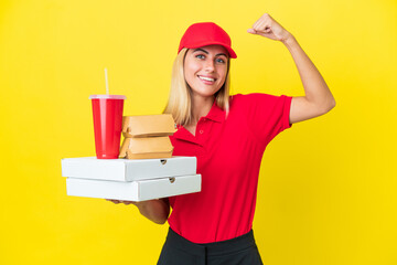 Delivery Uruguayan woman holding fast food isolated on yellow background doing strong gesture