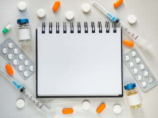 Syringes, injection vials and a notepad page for your inscription lying on the table. Close-up,...
