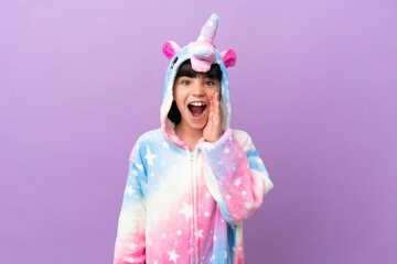 Little kid wearing a unicorn pajama isolated on purple background with surprise and shocked facial expression