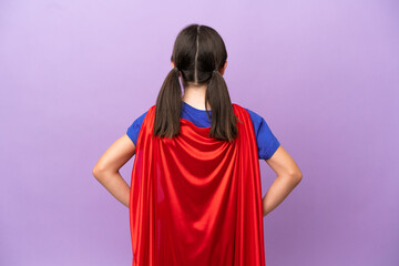 Little kid isolated on purple background in superhero costume in back position © luismolinero