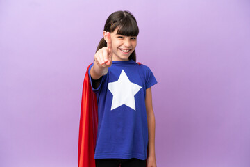 Little kid isolated on purple background in superhero costume and pointing to the front © luismolinero