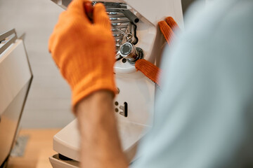 Male hands repairing coffee machine in cafe