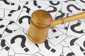 Legal questions and answers concept. Wooden judge gavel on question marks background.