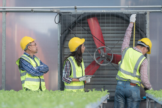 Engineers construction inspection structure of ventilation fan system for greenhouse for cultivation of vegetable clean food. Technician workers repairing mechanical system for clean fresh air. - Powered by Adobe