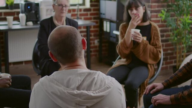 Man with anger management issues talking to people and counselor at aa group meeting to cure mental health problems. Angry adult discussing about alcohol addiction and depression.