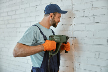 Male builder drilling wall with hammer drill