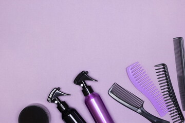 Hair styling product bottles with combs on purple background. Flat lay. Copy space