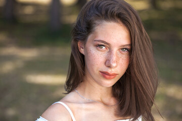 Fototapeta premium Young beautiful brown-haired girl with freckles on her face