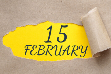 february 15. 15th day of the month, calendar date.Hole in paper with edges torn off. Yellow...