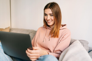 Happy interested young woman reading on a laptop computer