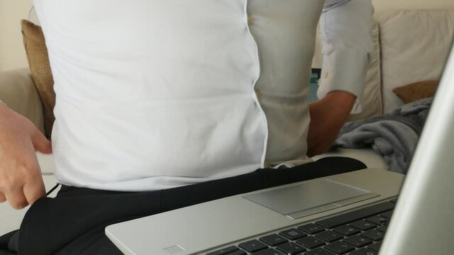 Fat belly man working from home on laptop with tight work shirt