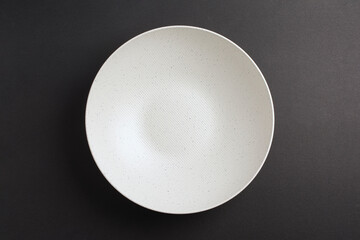Top down minimalist view of a white bowl on yellow background. White round plate on grey black background	